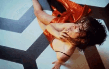 a woman in a red dress is laying on the floor with a man holding her
