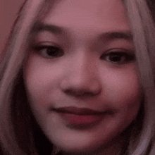 a close up of a woman 's face with a pink background and a blurred background .