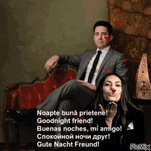 a man in a suit and tie is sitting on a red couch next to a woman who is blowing a kiss