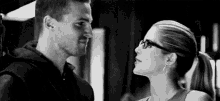 a black and white photo of a man and a woman looking into each other 's eyes .