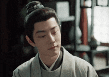 a man with his hair in a bun looks down at something