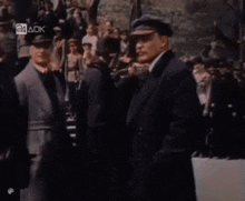 a group of men in suits and hats are standing in front of a crowd with the letters 24 aok on the bottom