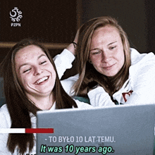 two women are looking at a laptop screen with the words to bylo 10 lat temu it was 10 years ago on the bottom