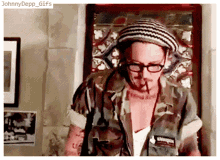 a man wearing a striped hat and glasses is smoking a cigarette with the caption johnnydepp gifs