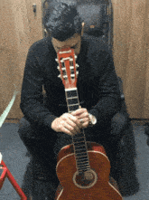 a man is playing an acoustic guitar with the letter t on the headstock