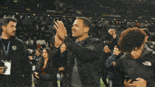 a man in a black jacket is applauding in front of a building on success sign