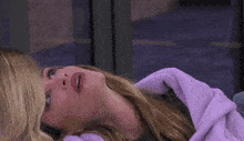 a woman is laying on a bed with a purple blanket and looking up at the sky .
