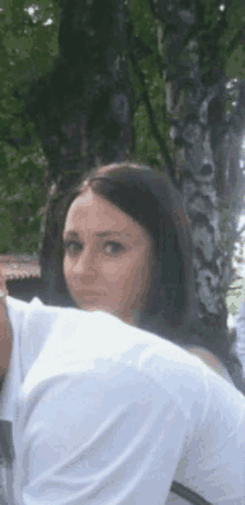 a woman in a white shirt looks over a man 's back