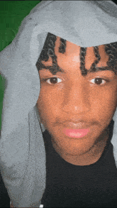 a young man with curly hair is wearing a gray cloth on his head