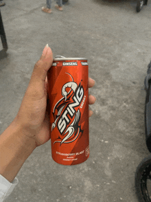 a person holds a can of sting energy drink