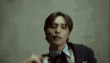 a man in a suit and tie is standing in front of a wall and crying .