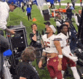 a group of football players are standing on a field with a cameraman .