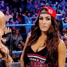 a woman wearing a red hat with the number 8 on it stands in a wrestling ring