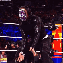 a wrestler with a purple mask on his face is standing in the ring .