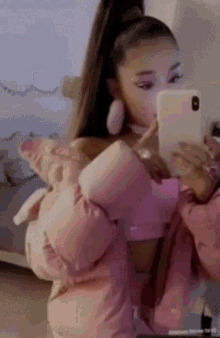 ariana grande is taking a picture of herself in a mirror with her phone .