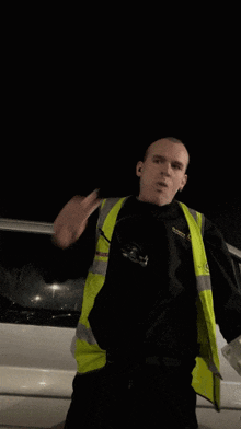 a man wearing a black shirt and a yellow vest stands in front of a van