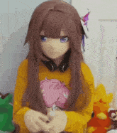 a girl wearing a mask and a yellow sweater is holding a stuffed animal .