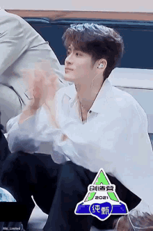 a young man in a white shirt and black pants is kneeling down and clapping .