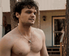 a shirtless man wearing a necklace with a key pendant on it