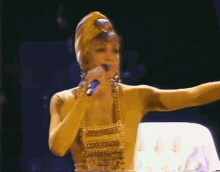 a woman is singing into a microphone while wearing a turban