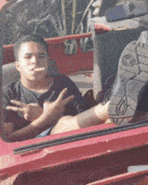a man smoking a cigarette while sitting in a red car