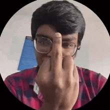 a young man wearing glasses is making a middle finger gesture .