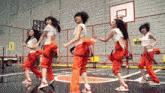 a group of women are dancing on a basketball court in front of a sign that says " do not enter "