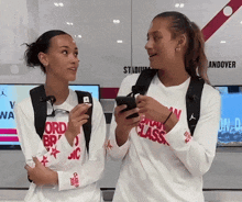 two women standing next to each other in front of a wall that says stadium anddover