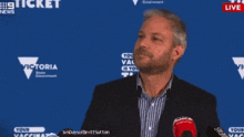 a man stands in front of a blue wall that says victoria