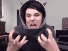 a man is wearing a hoodie with horns on it and making a funny face .