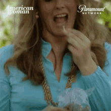 a woman in a blue shirt is eating something from a bag with paramount network written on it