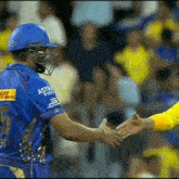 a cricket player is shaking hands with another cricket player during a game .