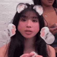 a woman with cat ears and paws on her head looks at the camera .
