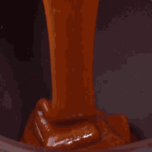 a bowl of sauce is being poured into a chocolate bowl