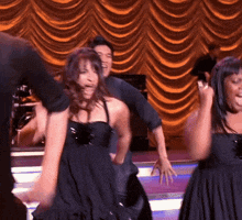 a group of people are dancing on a stage with a yellow curtain in the background