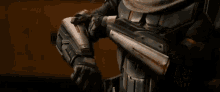 a man in a helmet and armor is standing in a room adjusting his helmet .