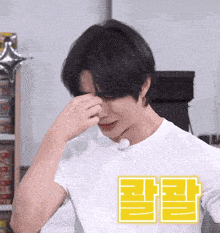 a man in a white shirt is covering his face with his hand and has a yellow square with chinese writing on it