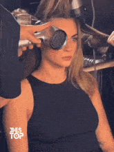 a woman is getting her hair blow dried by a hairdresser with the words es top on the bottom