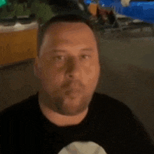 a man in a black shirt is smiling in front of a trash can .