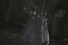 a woman in a white dress is standing in a dark room holding a broom in her hand .