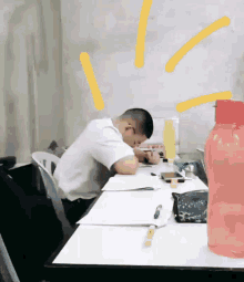 a man is sitting at a desk with a pink water bottle in front of him