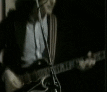 a man is playing a guitar and singing into a microphone .