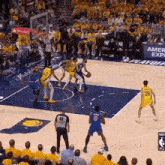 a group of basketball players are playing a game of basketball on a court in front of a crowd .