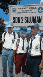 three people standing in front of a sign for sdn 2 siluman