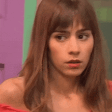 a woman with long hair and bangs is making a funny face .