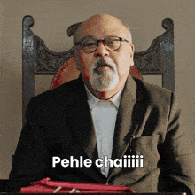 a man with glasses and a beard is sitting in a chair and says pehle chaiii