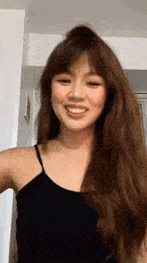 a woman in a black tank top smiles for the camera