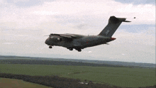 a military plane is flying over a field and has the letters cccp on its tail