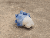 a blue and white unicorn figurine is laying on a gray surface