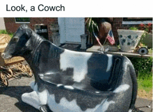 a black and white statue of a cow is sitting in front of a house